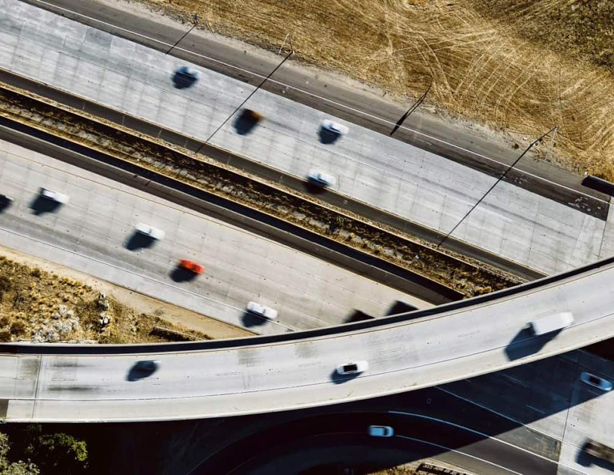 An aerial view of a highway with trucks and cars driving on the roadways and off ramps